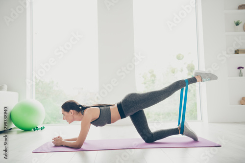 Full size profile side photo of joyful active girl do sport yoga exercises stretch legs hips put elbows on violet mat in house like fitness studio
