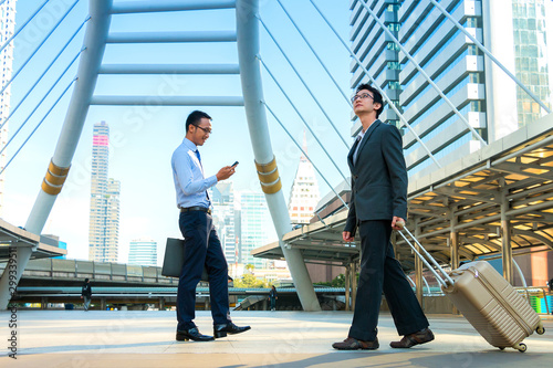 Two young business men walking with city background.
