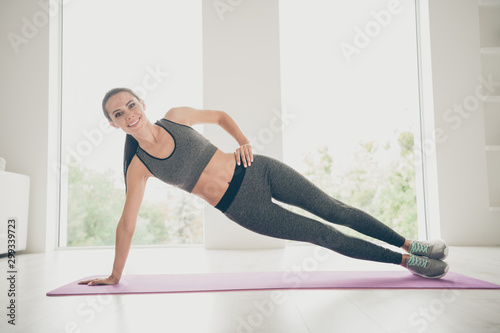 Full body photo of sporty girl having sport wear pants practice in her home house gym-like studio stretch legs arms