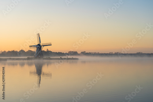 Nature awakens at a traditional Dutch windmill during a foggy dawn. De Helper, Groningen.