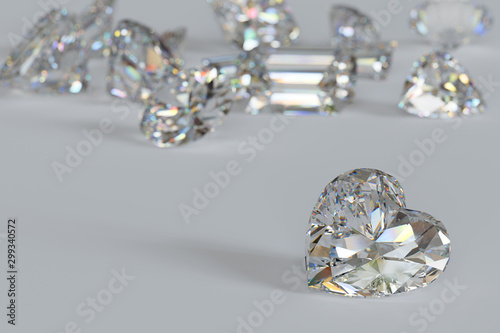 Variously cut diamonds scattered on white background with a heart cut stone on foreground.