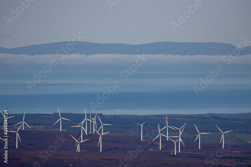 Coastal wind farm in Scotland on land near the moray firth with mountain, cloud, and sky background.