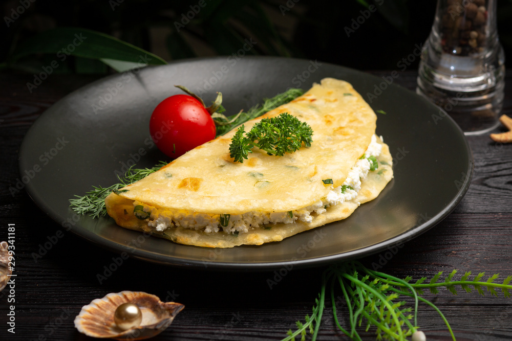 Chinese onion tortilla with cottage cheese and herbs in a black plate