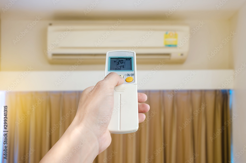 Air conditioner inside the room, Man's hand using remote control open The air conditioner in his bedroom. Health concepts and energy savings Air conditioner inside the room, Man's hand using remote control open The air conditioner in his bedroom. Health concepts and energy savings