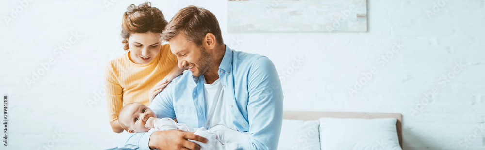 happy parents smiling while sitting on bed with little daughter happy parents smiling while sitting on bed with little daughter