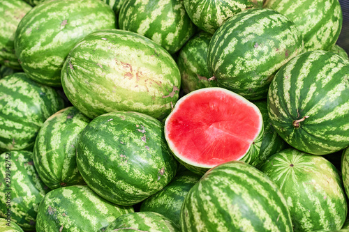 A total plan of a pile of watermelons on which lies the cut half of the watermelon. Half of the watermelon pitted ready for sale. Trade watermelons outdoors.