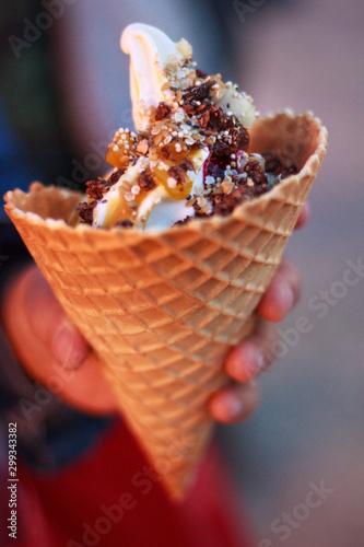 Hand with Frozen Yogurt with caramel topping in a cone photo