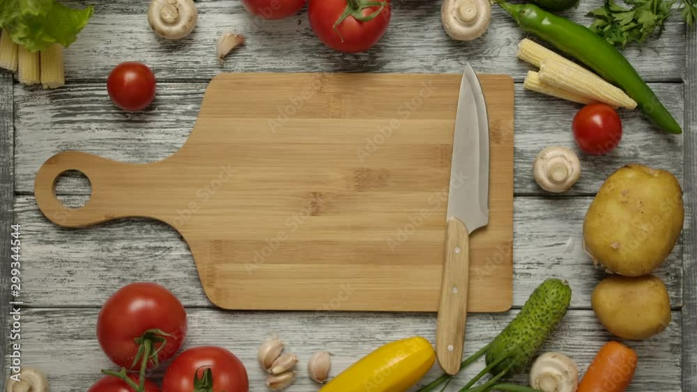 A human hand taking half an orange paprika from a cutting board. Knife and other vegetables for cooking vegetarian food on the wooden table. A human hand taking half an orange paprika from a cutting board. Knife and other vegetables for cooking vegetarian food on the wooden table.