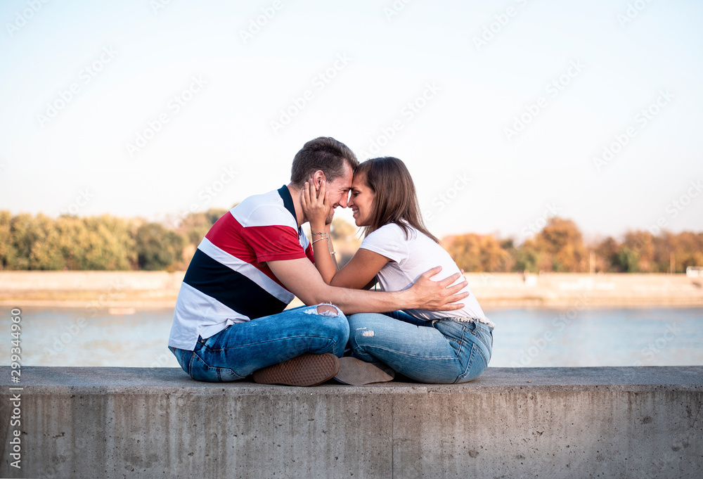 Happy casual young loving couple in jeans, sitting facing each other