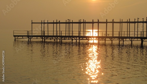 old wooden pier with silhouettes of seagulls at sunset quiet autumn evening