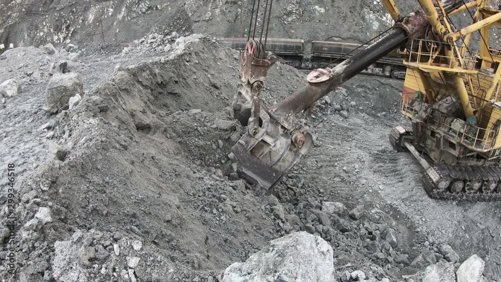 The excavator loads the stones into the cars. Loading ore into the railway cars in the quarry.