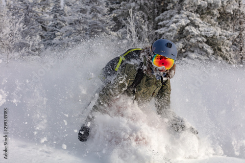 beauty Freerider. snowboarder is riding with snowboard from powder snow hill or mountain forest. Extreme winter sports. off-piste snowboarding in the woods with big swirls of fresh snow in the air