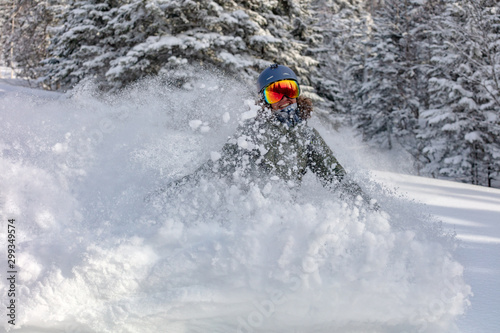 freerider in a bright suit rides snowboarding with large splashes of snow on a sunny day. Young Beautiful female snowboarder. concept snowboard. big swirls of fresh snow in the air