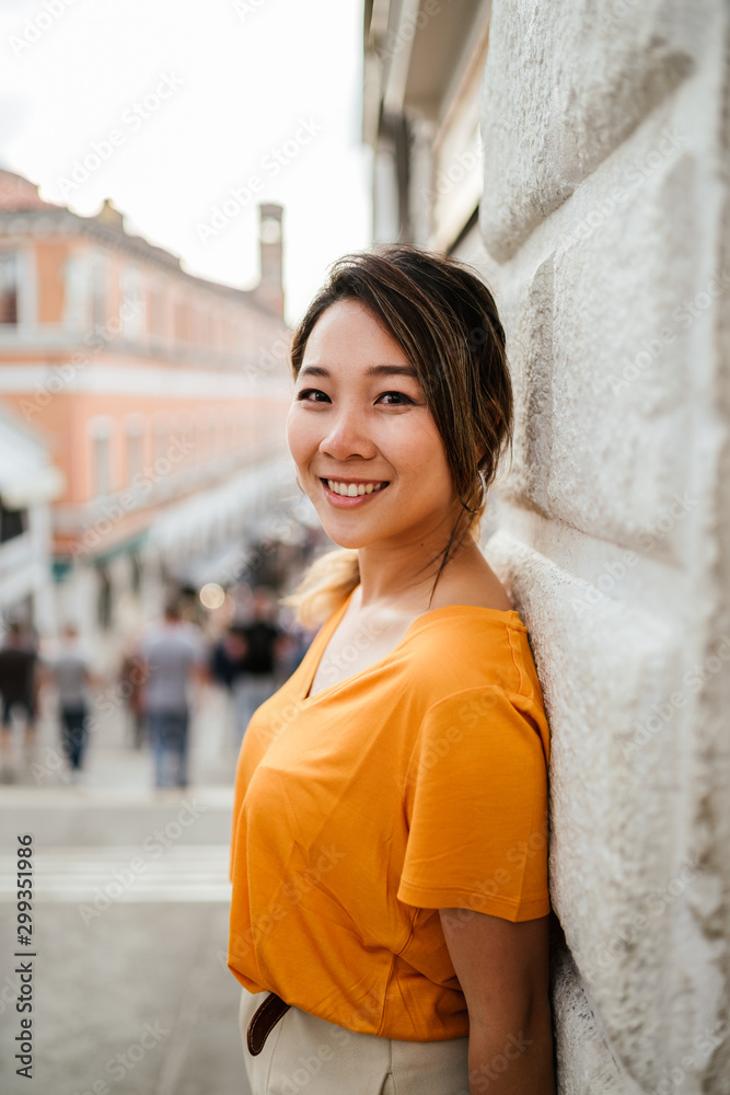 Portrait of a beautiful and young Asian girl on vacation at sunset in Venice, Italy - Millennial smiles at the camera
