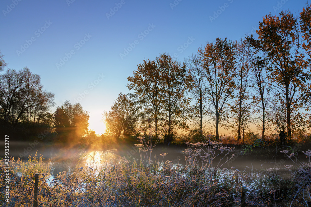sunrise over a foggy lake on a cold autumn morning