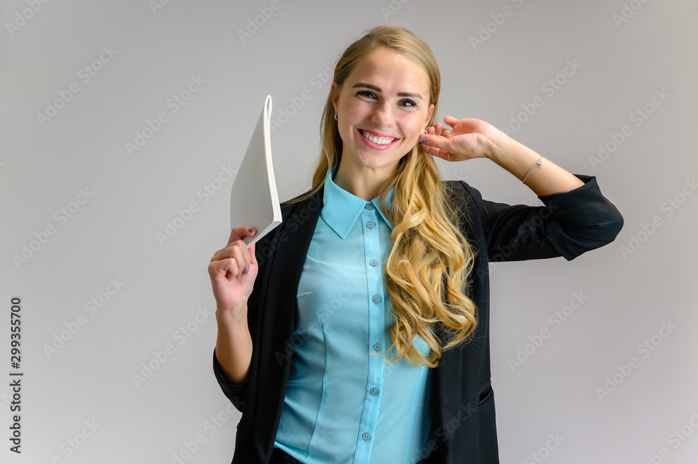 Portrait of a pretty blonde girl financial secretary with long curly hair in a business suit standing in the studio on a white background with emotions in different poses with a folder in his hands. Portrait of a pretty blonde girl financial secretary with long curly hair in a business suit standing in the studio on a white background with emotions in different poses with a folder in his hands.