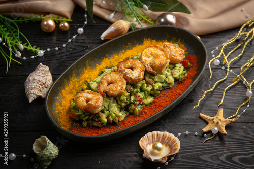 tartar shrimp with avocado and spices on a black oval plate