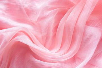 Delicate pink organza chiffon fabric background with swirl creased texture. Sewing fashion clothes making wedding women's apparel concept