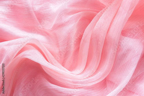 Delicate pink organza chiffon fabric background with swirl creased texture. Sewing fashion clothes making wedding women's apparel concept