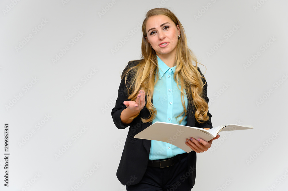 Portrait of a pretty blonde girl financial secretary with long curly hair in a business suit standing in the studio on a white background with emotions in different poses with a folder in his hands. Portrait of a pretty blonde girl financial secretary with long curly hair in a business suit standing in the studio on a white background with emotions in different poses with a folder in his hands.