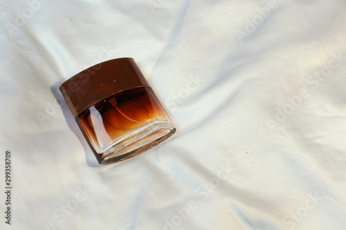 Brown fashion trendy bottles of perfume toilet water fragrances  lie on a silver gray sheet on the bed, top view. Female and male fragrances 