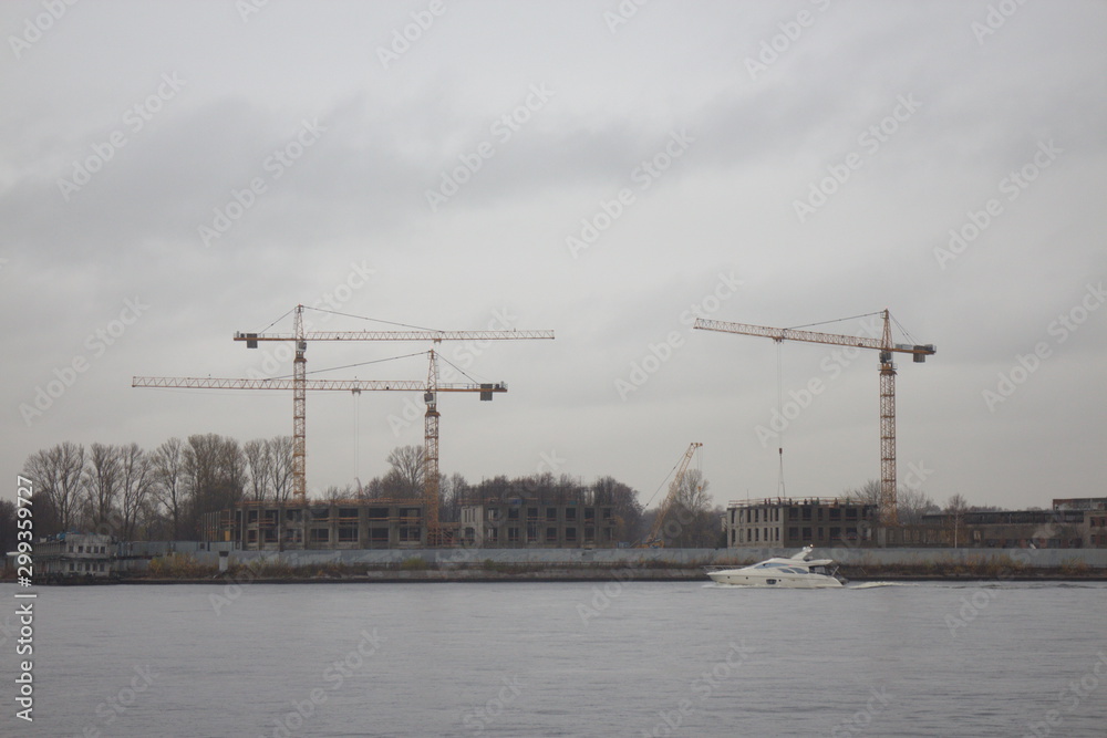 Obraz premium tower cranes on the shore on a cloudy day