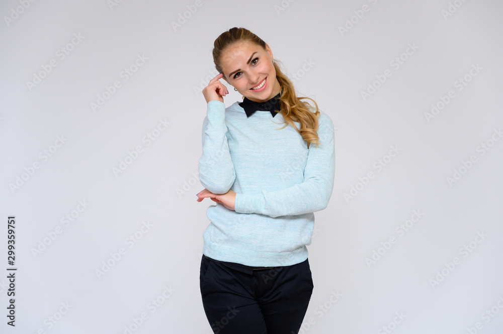 Portrait of a pretty blonde financial secretary girl with long curly hair in a business suit standing in the studio on a white background with emotions in different poses. Portrait of a pretty blonde financial secretary girl with long curly hair in a business suit standing in the studio on a white background with emotions in different poses.