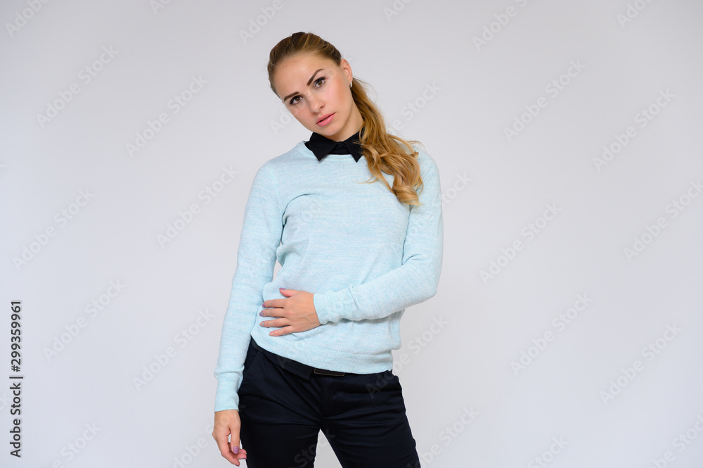 Portrait of a pretty blonde financial secretary girl with long curly hair in a business suit standing in the studio on a white background with emotions in different poses. Portrait of a pretty blonde financial secretary girl with long curly hair in a business suit standing in the studio on a white background with emotions in different poses.