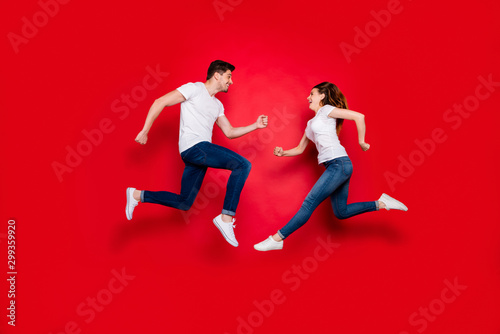 Side profile full length body size photo of cheerful positive pretty couple boyfriend girlfriend running into each other jumping jeans denim white t-shirt footwear isolated vivid color background