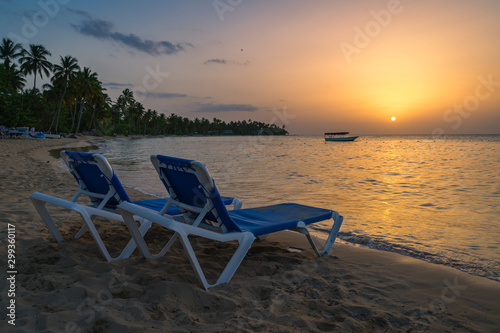 Two beach chairs and boat background on the tropical beach at sunset,Dominican republic,Bahia Principe beach. © robertobinetti70