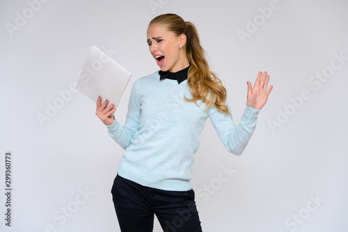 Portrait of a pretty blonde girl financial secretary with long curly hair in a business suit standing in the studio on a white background with emotions in different poses with a folder in his hands.