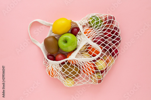 Cotton mesh shopping bag with fruit on pink background. Zero waste concept. Caring for the environment and the rejection of plastic. 