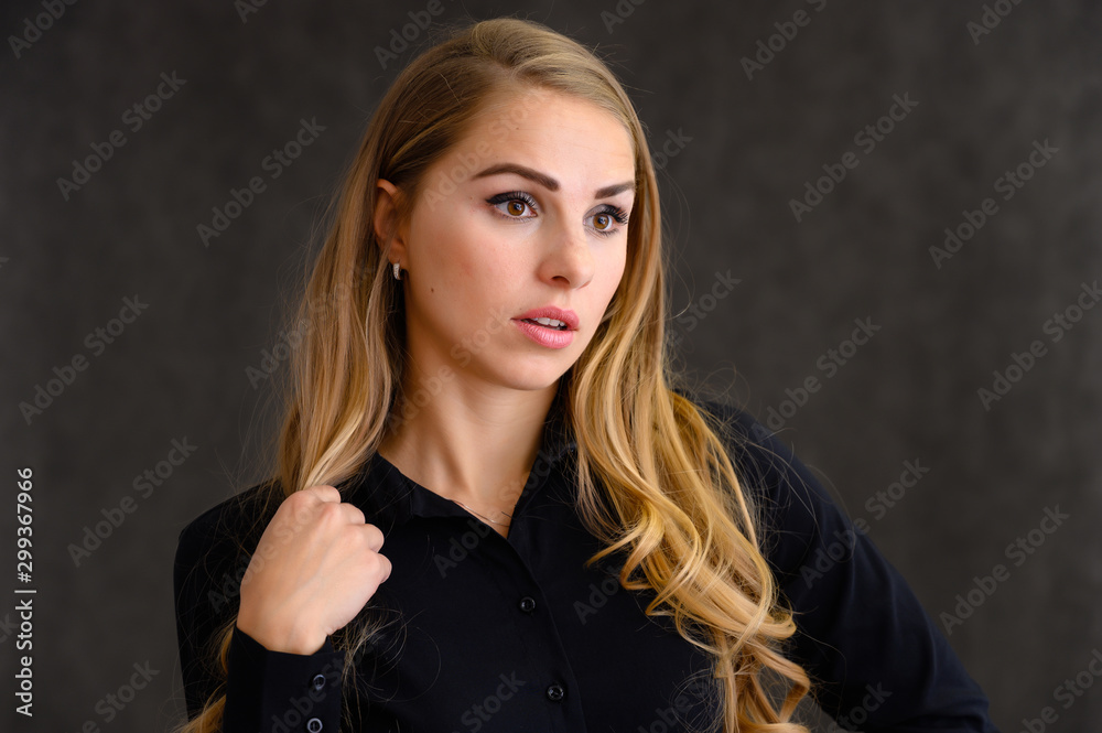 Close-up portrait of a pretty blonde girl with long curly hair standing in the studio on a gray background with emotions in different poses. Beauty, Model, Cosmetics Close-up portrait of a pretty blonde girl with long curly hair standing in the studio on a gray background with emotions in different poses. Beauty, Model, Cosmetics