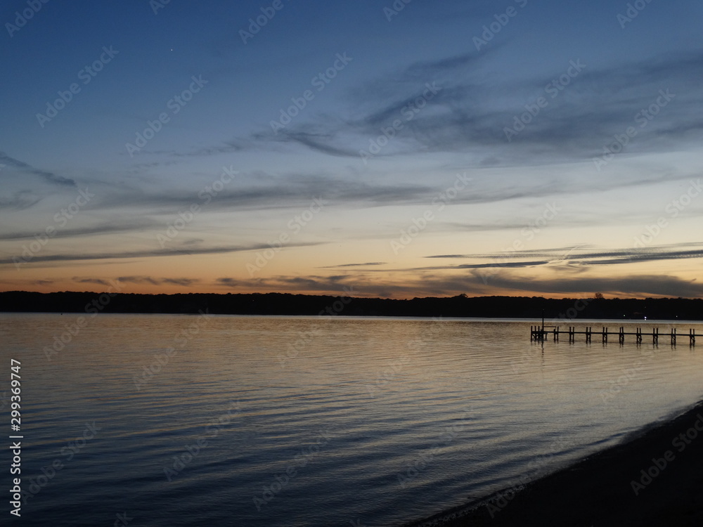 sunset on calm Shinnecock Bay in Hamptons with gray clouds and pier #1