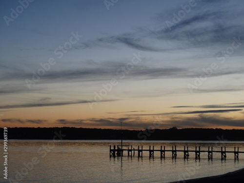 sunset on calm Shinnecock Bay in Hamptons with gray clouds and pier  2