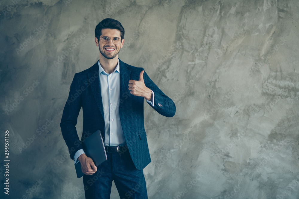 Photo of cheerful toothy positive man holding laptop showing you thumb up with stubble near empty space isolated grey color background Photo of cheerful toothy positive man holding laptop showing you thumb up with stubble near empty space isolated grey color background