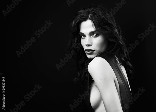 Fashion vogue style studio portrait. Young sexy girl in black leather dress and ring, posing on the black background. Woman vogue style black leather. Beautiful long black straight hair and make up.