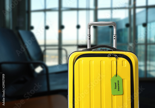 фотографія Yellow suitcase with TRAVEL INSURANCE label in airport terminal
