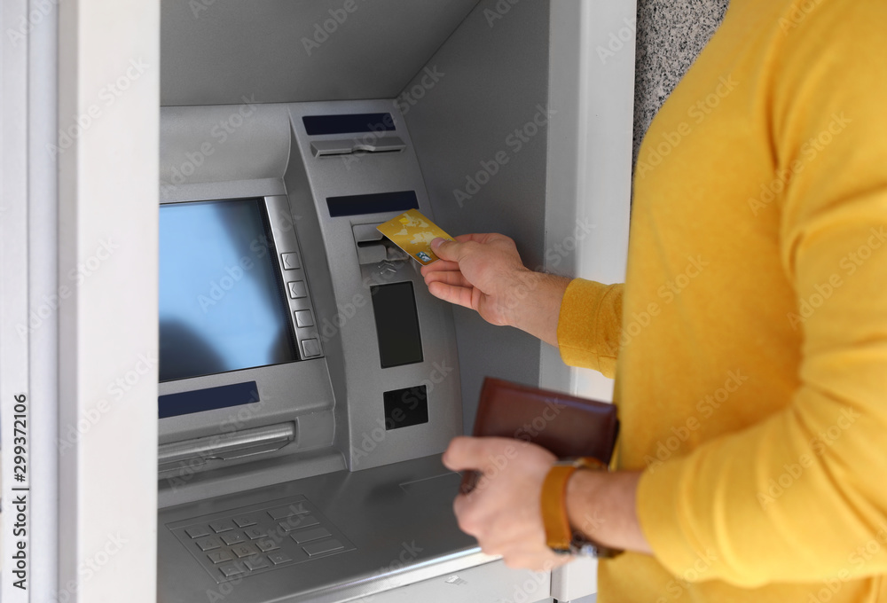 Young man using modern cash machine outdoors, closeup Young man using modern cash machine outdoors, closeup