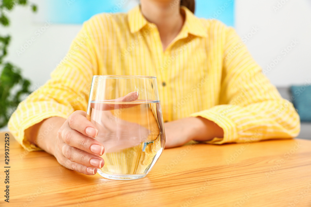 Woman holding glass of water at wooden table, closeup with space for text. Refreshing drink Woman holding glass of water at wooden table, closeup with space for text. Refreshing drink