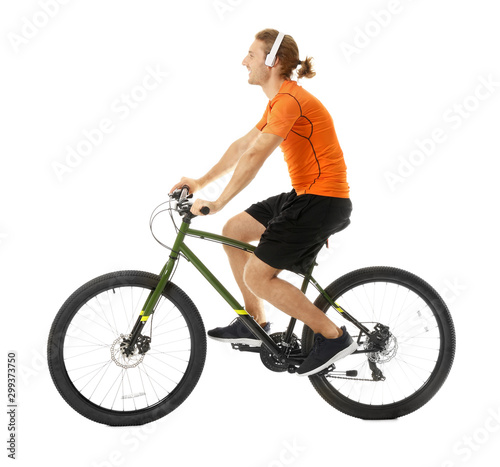 Happy young man with headphones riding bicycle on white background © New Africa
