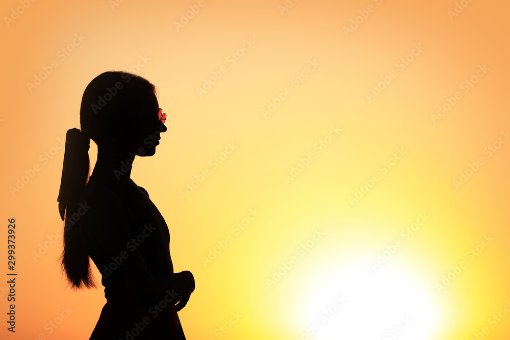 Silhouette of young woman outdoors at sunset