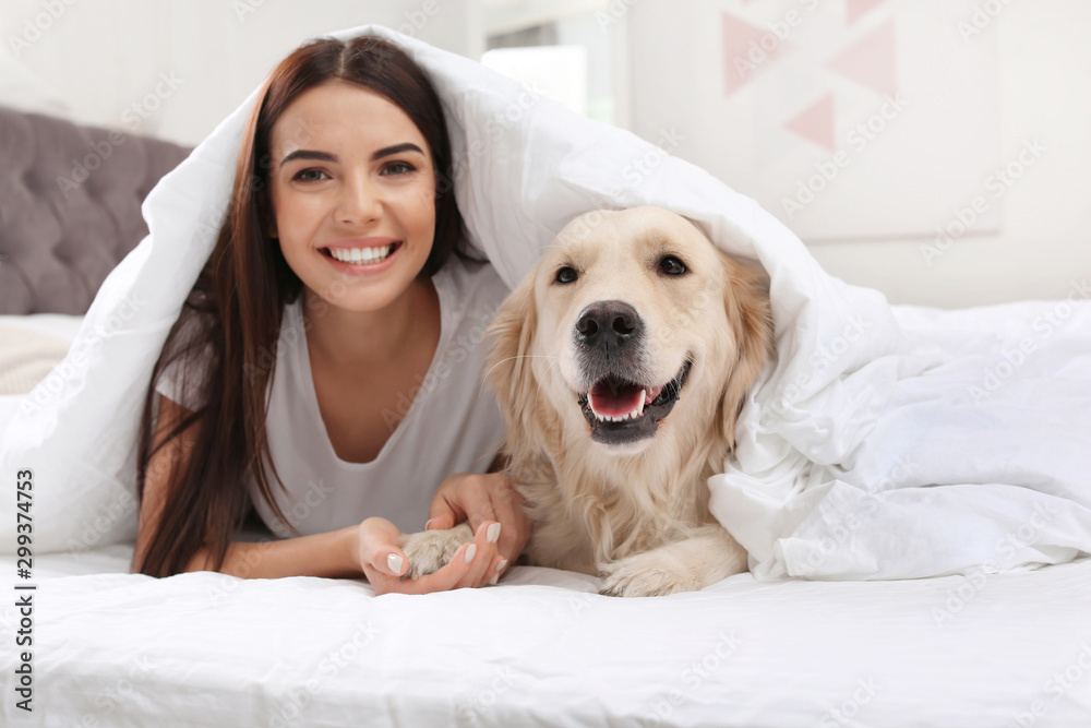 Young woman and her Golden Retriever dog on bed at home Young woman and her Golden Retriever dog on bed at home