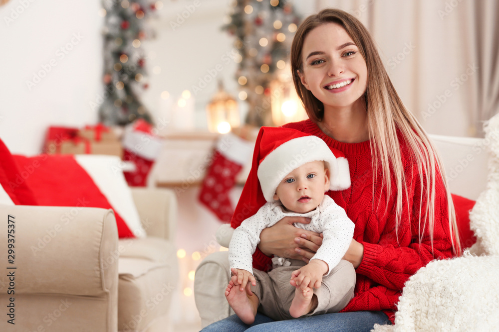 Happy mother with cute baby in room decorated for Christmas holiday Happy mother with cute baby in room decorated for Christmas holiday
