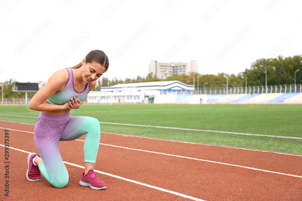 Young woman having heart attack while running at stadium Young woman having heart attack while running at stadium