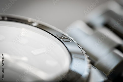 Extreme close-up of the rotating bezel and hour marker seen on an iconic, swiss-made divers watch. Part of the watch crystal and steel links are visible.