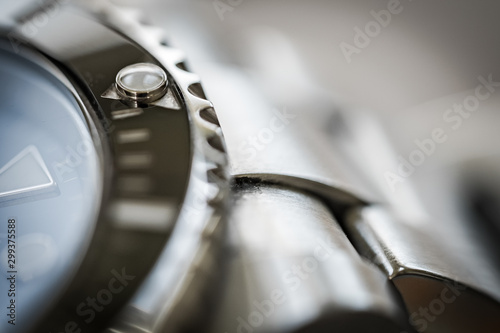 Extreme close-up of the rotating bezel and hour marker seen on an iconic, swiss-made divers watch. Part of the watch crystal and steel links are visible.
