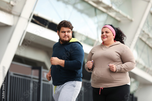 Overweight couple running together outdoors. Fitness lifestyle