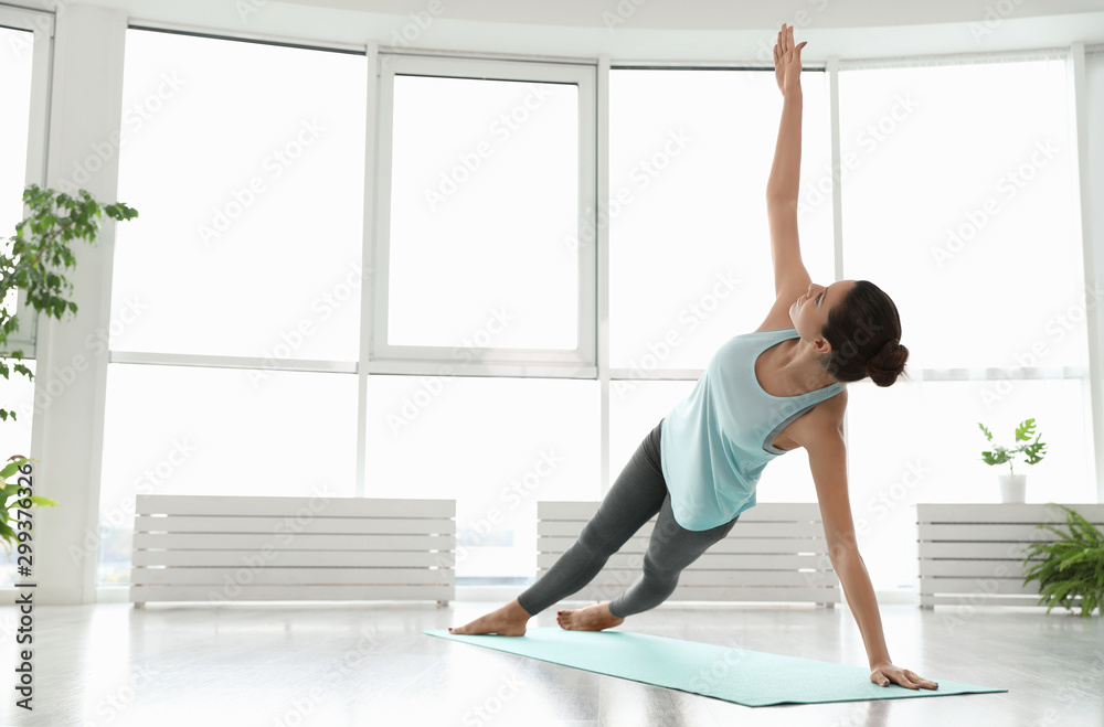 Young woman practicing side plank asana in yoga studio. Vasisthasana pose