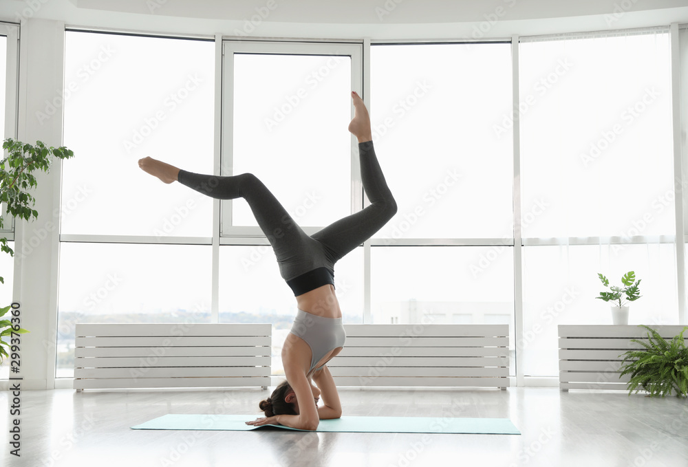 Young woman practicing headstand with splits in yoga studio Young woman practicing headstand with splits in yoga studio